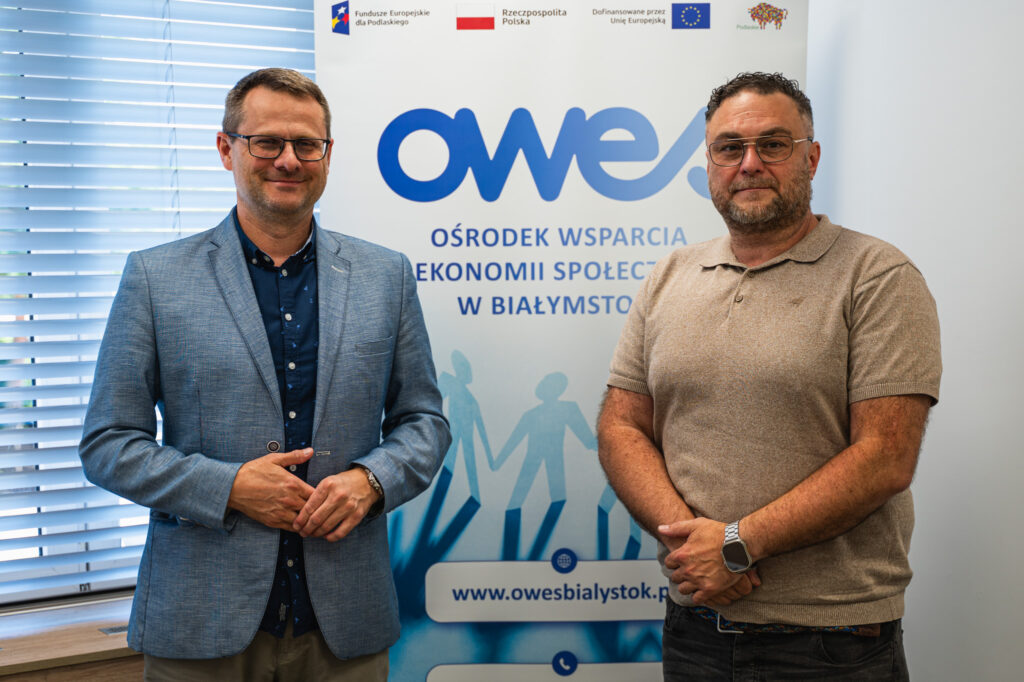 Dwaj mężczyźni stoją na tle rollupa z logo OWES.