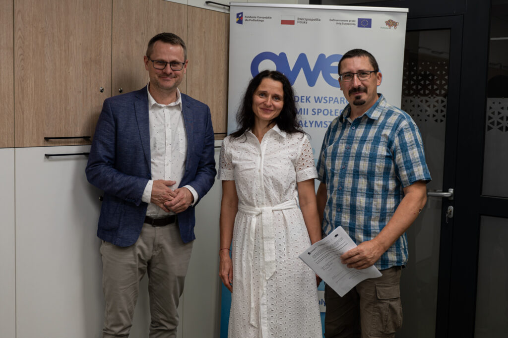 Dwóch mężczyzn i kobieta stoją z podpisaną umową