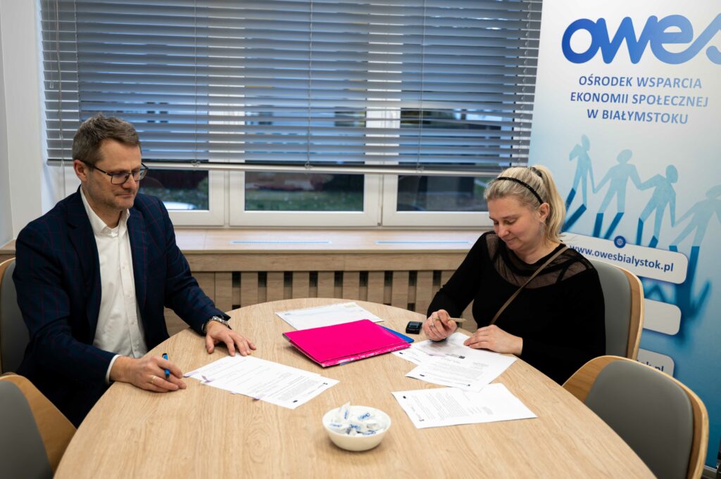 Mężczyzna i kobieta siedzą przy stole z dokumentami.