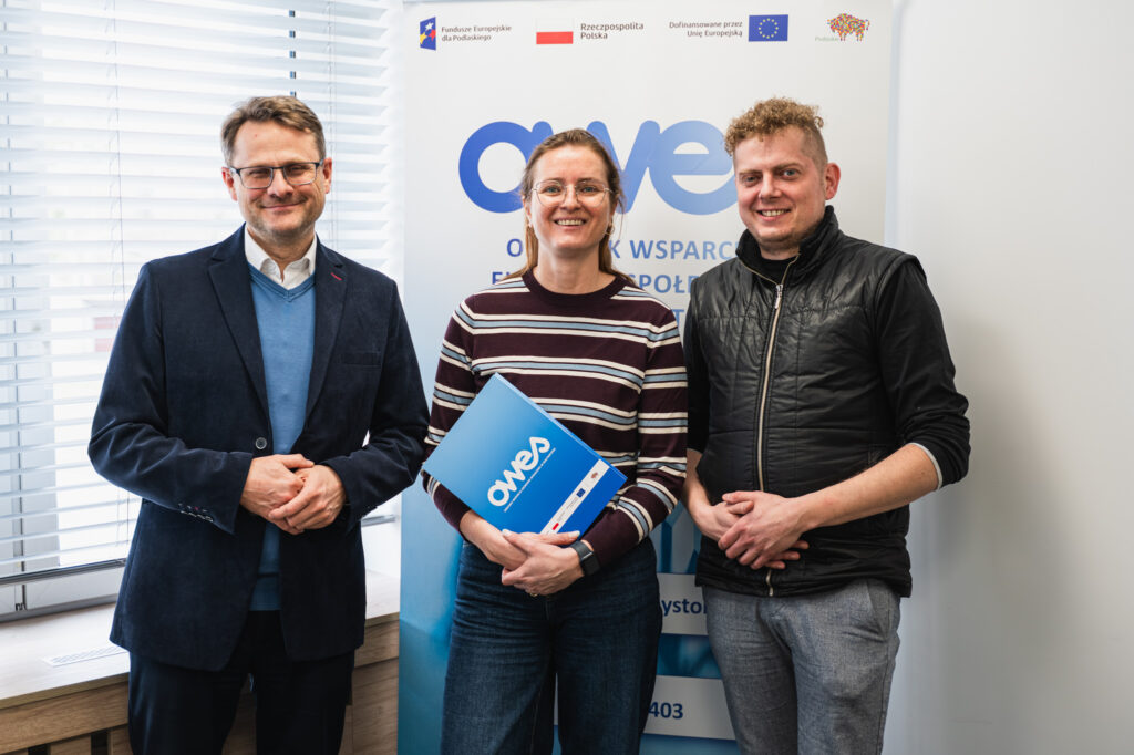 Dwaj mężczyźni i kobieta stoją obok siebie. kobieta trzyma w ręku umowę.