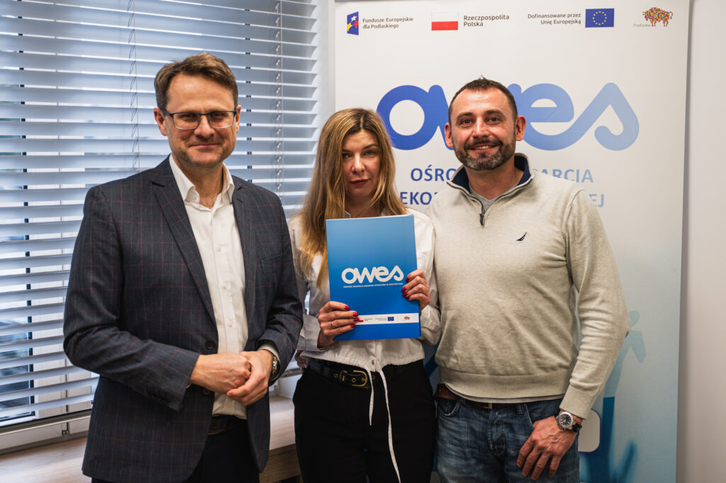 Dwóch mężczyzn i kobieta stoją z umową OWES