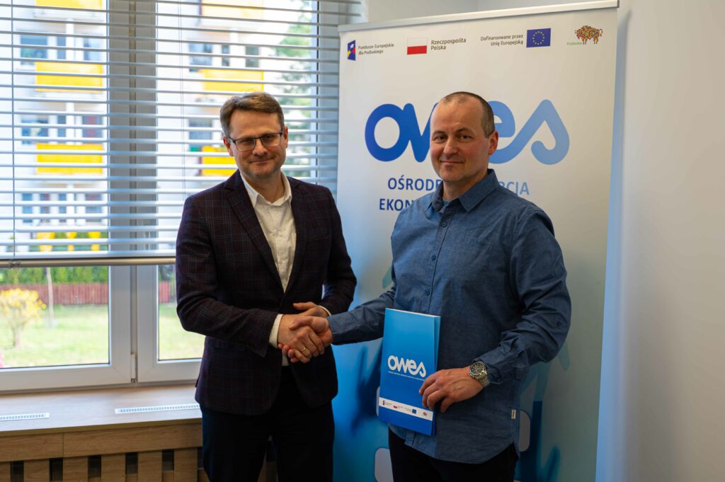 Dwóch uśmiechniętych mężczyzn w średnim wieku podaje sobie ręce.