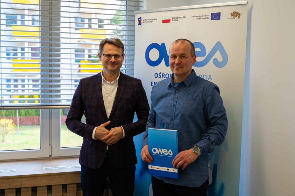 Dwaj uśmiechnięci mężczyźni w średnim wieku stoją z podpisana umową.