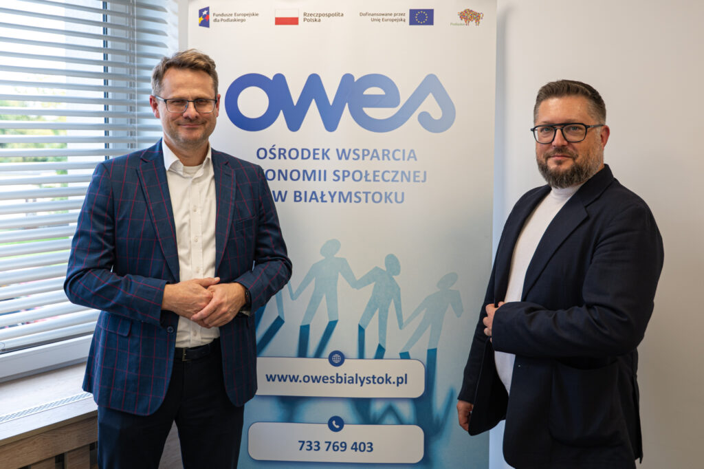 dwóch mężczyzn stoi na tle rollupu z napisem OWES.