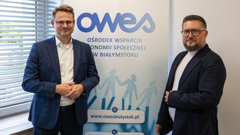 dwóch mężczyzn stoi na tle rollupu z napisem OWES.