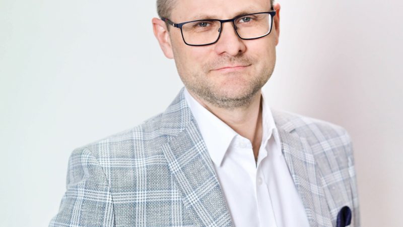 Mężczyzna w okularach lekko się uśmiecha