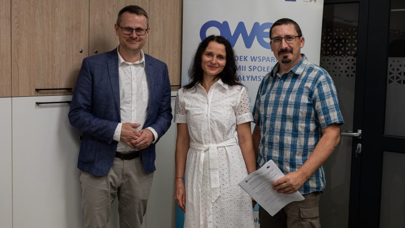 Dwóch mężczyzn i kobieta stoją z podpisaną umową