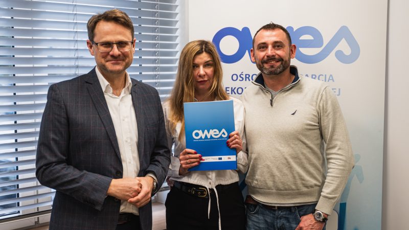 Dwóch mężczyzn i kobieta stoją z umową OWES
